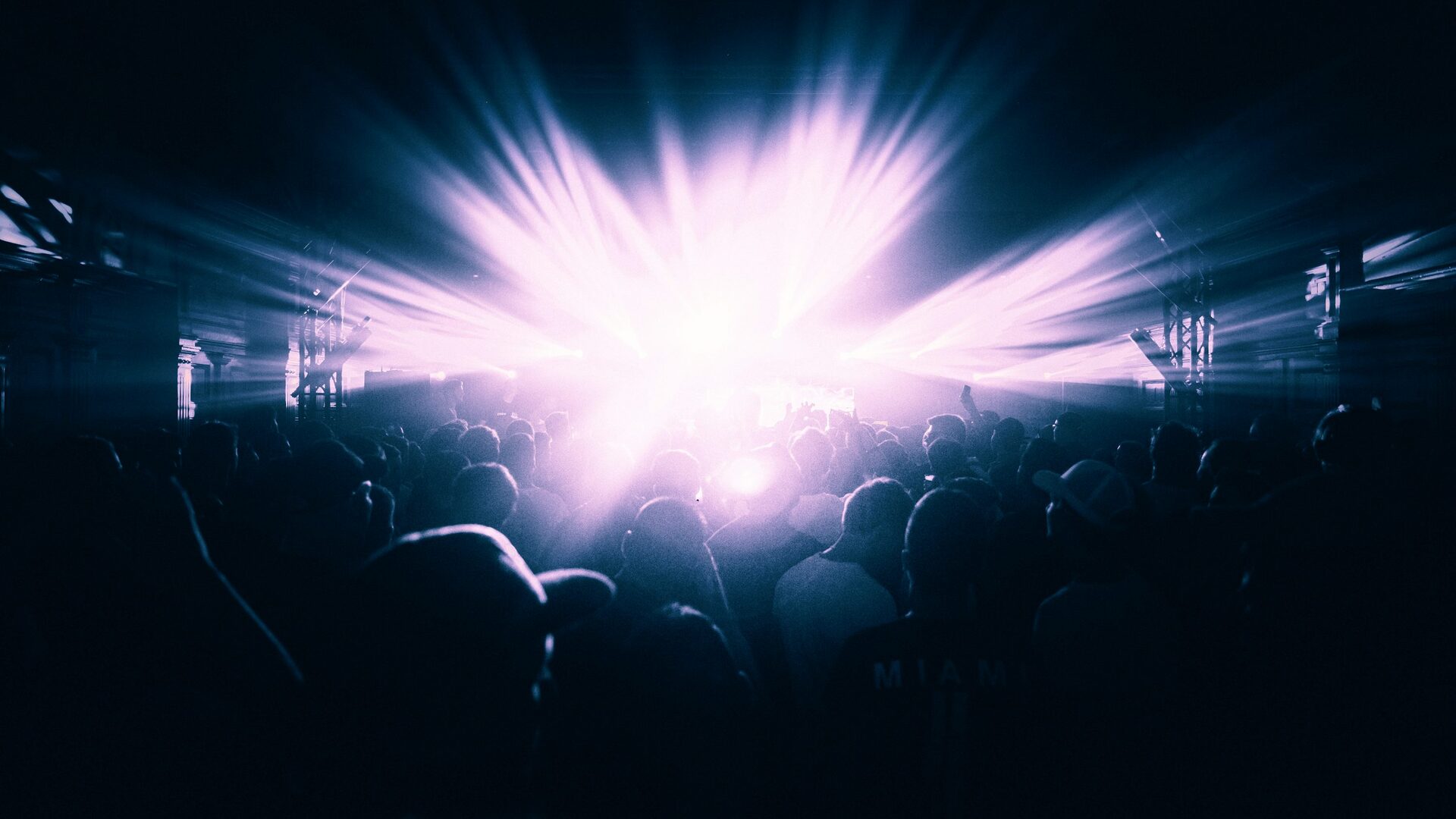 Club crowd going wild with purple blue lighting and mosh pit energy