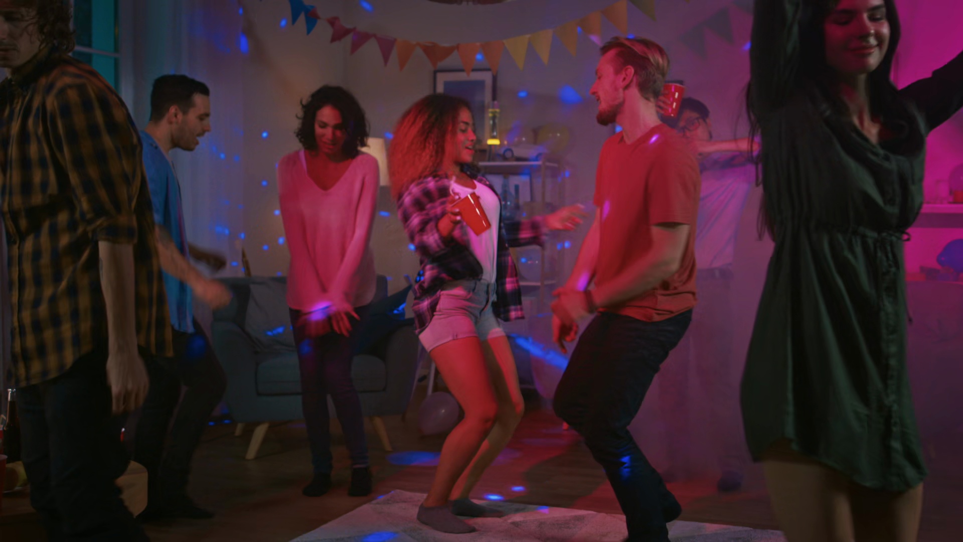 College house party with colorful lights and young crowd dancing